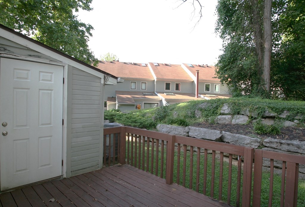 A deck with a white door and a brown railing.