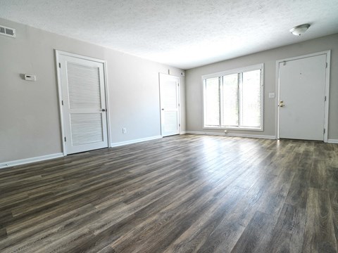 A room with wooden flooring and three doors.