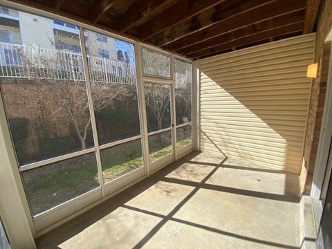 A sunny day with a view of a tree and a building through a sliding glass door.