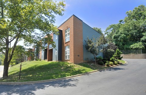 A modern building with a grey roof and a green lawn in front.