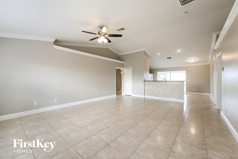 a spacious living room with tile flooring and a ceiling fan