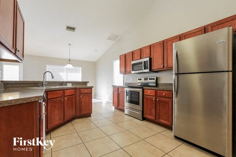 A kitchen with wooden cabinets and a stainless steel refrigerator.