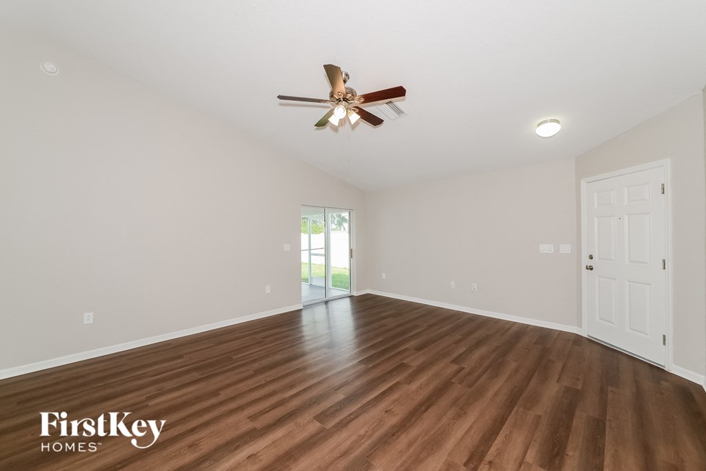 the spacious living room with hardwood floors and a ceiling fan
