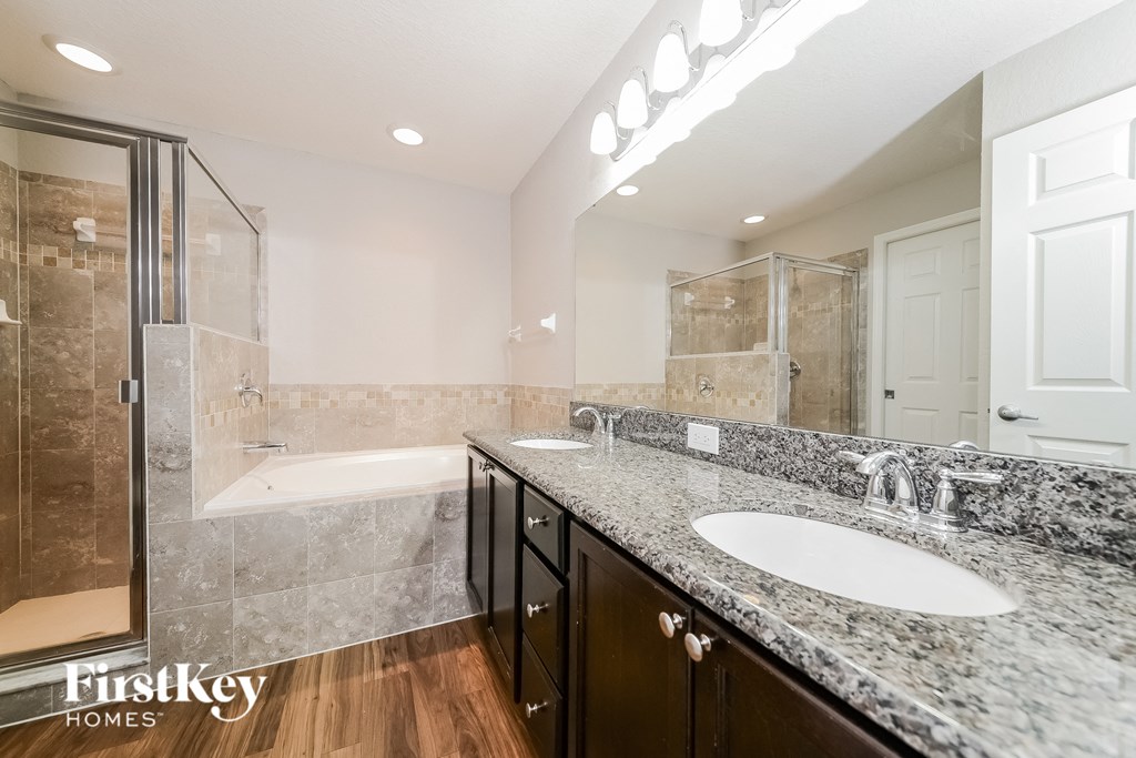 the master bathroom has dual sinks and a large shower and tub