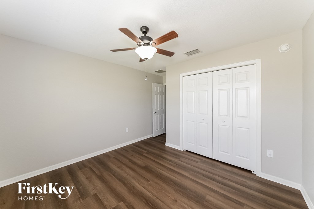 a bedroom with a ceiling fan and a door to a closet