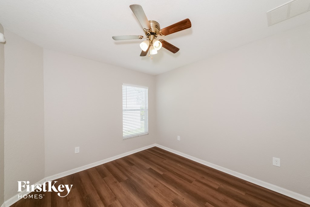 a bedroom with a ceiling fan and wood floors