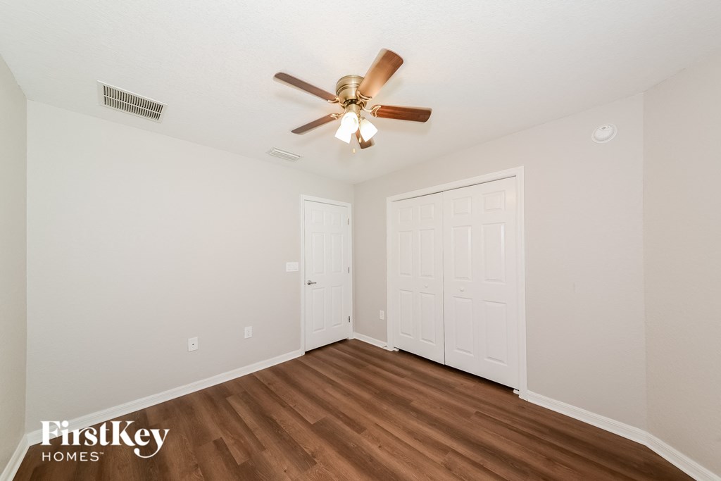 a bedroom with a ceiling fan and a door to a closet
