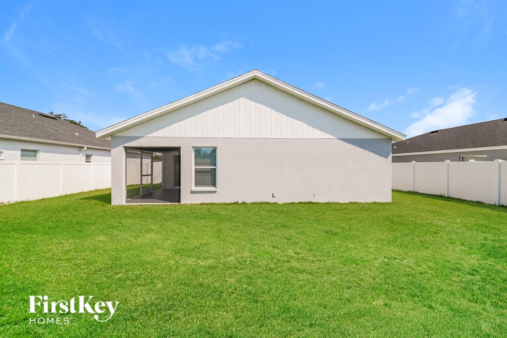 a backyard with a white house and a green lawn