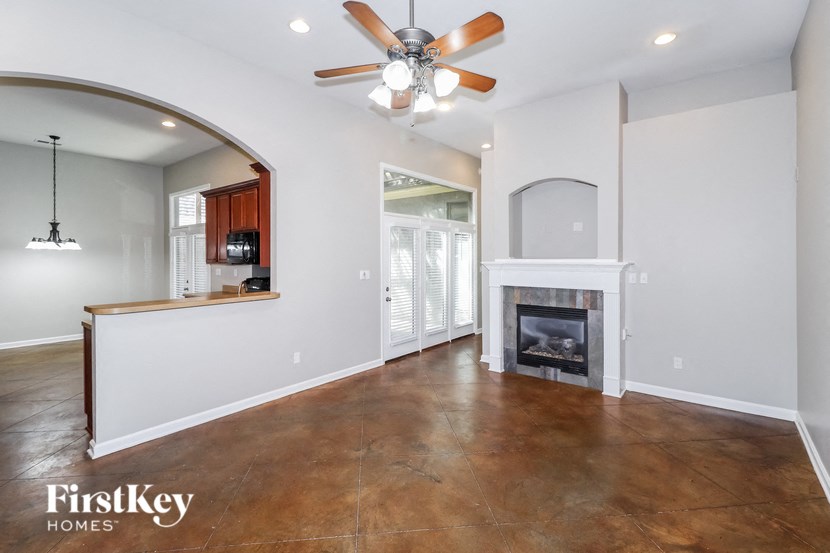 A living room with a fireplace and a ceiling fan.