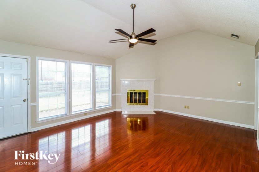 A spacious room with a fireplace and a ceiling fan.