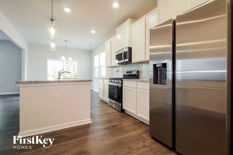 A modern kitchen with a stainless steel refrigerator and wooden floors.