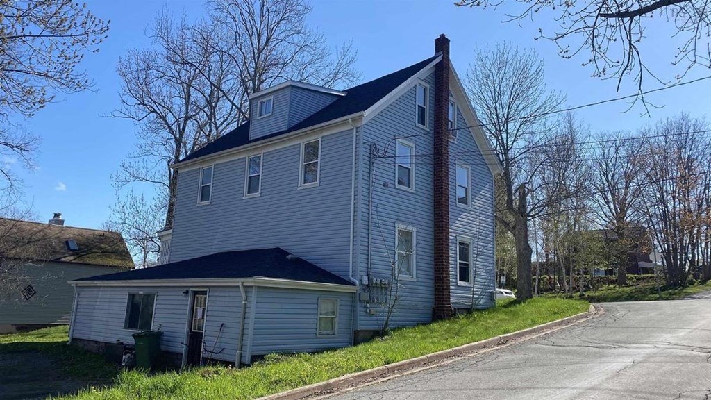 a gray house with a black roof on the side of a street