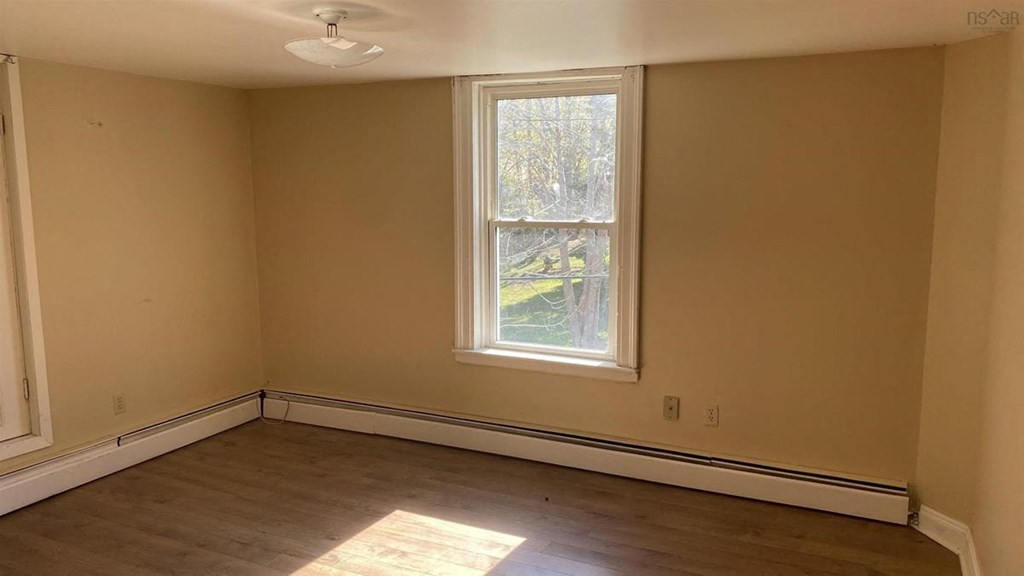an empty room with a window and wooden floors