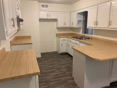 A kitchen with white cabinets and wooden countertops.