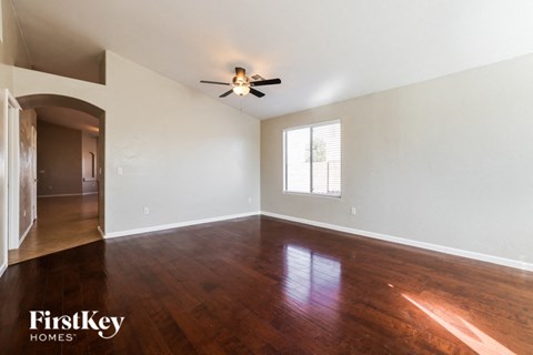 an empty living room with wood floors and a ceiling fan