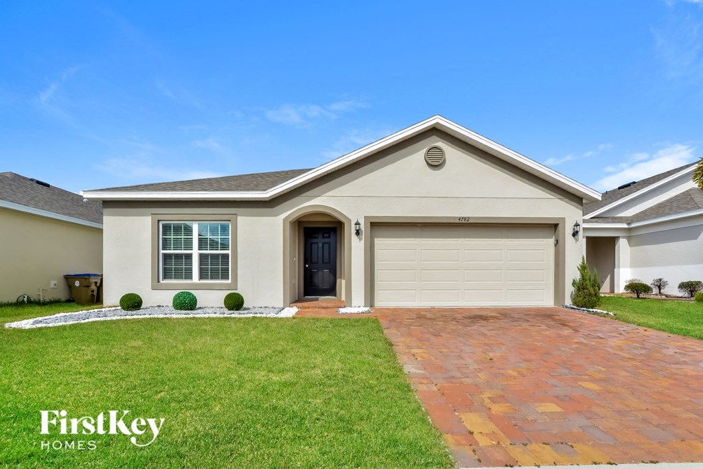 A house with a garage and a driveway in front of it.