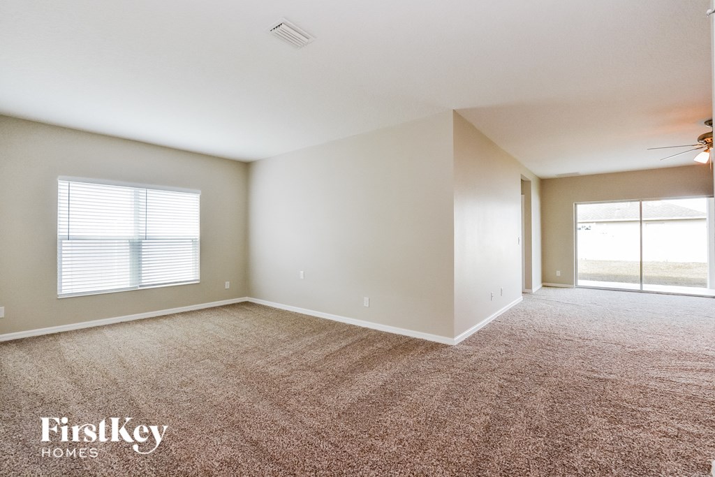 A spacious room with a carpeted floor and a sliding glass door leading to a balcony.