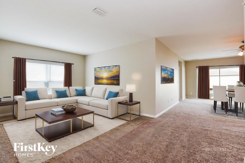 A well-lit living room with a white sofa and a coffee table in the center.