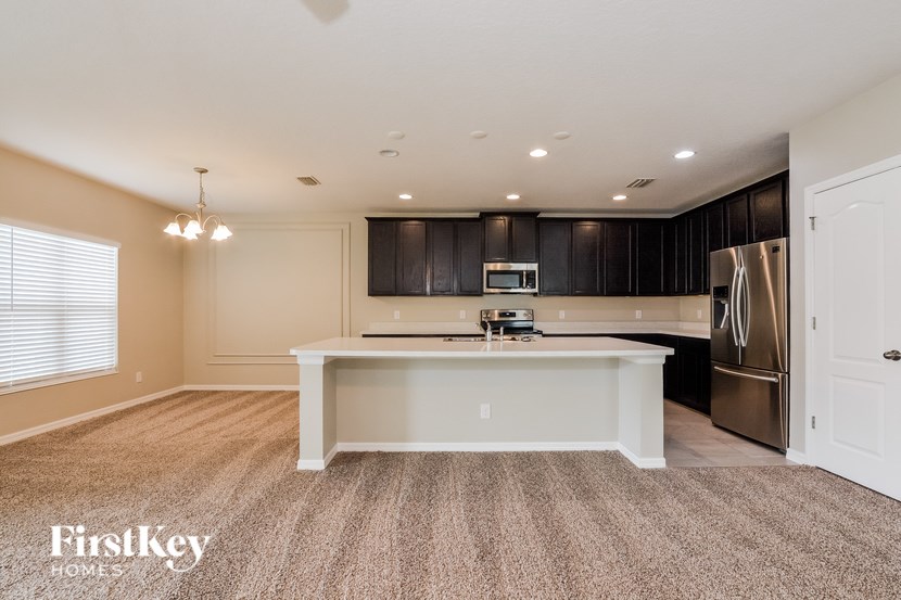 A kitchen with a white island and a refrigerator in a house.