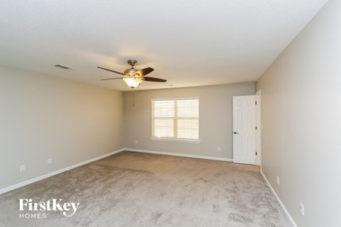 an empty living room with a ceiling fan and a window