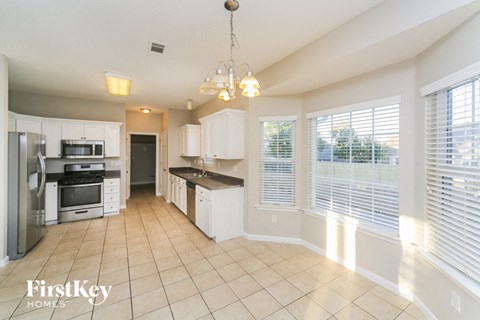 a large kitchen with white cabinets and a large window