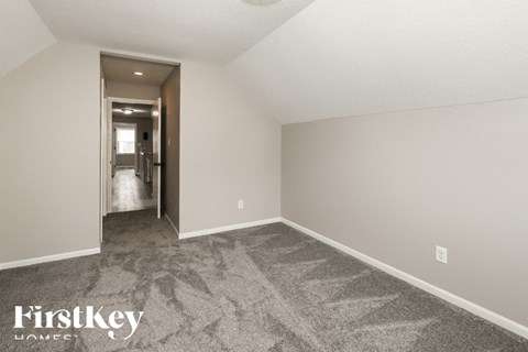 a spacious living room with carpet and a hallway to the bathroom