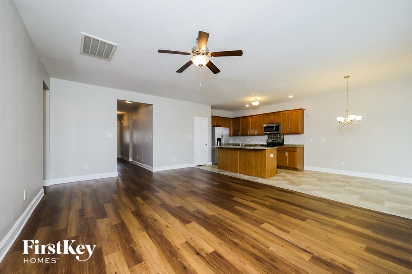 A spacious room with wooden floors and a ceiling fan.
