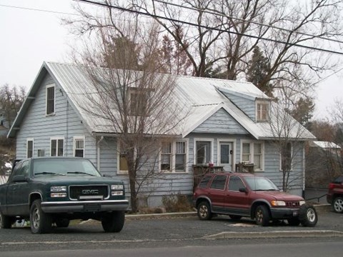 A blue house with a green truck parked in front.