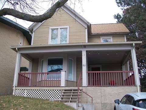A house with a balcony and a tree in front.