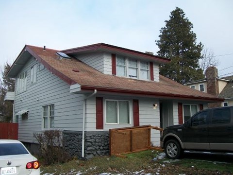 A house with a red roof and a car parked in front.