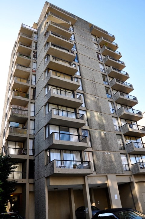 A tall concrete apartment building with balconies on each floor.