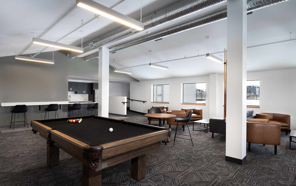 a common room with a pool table and chairs