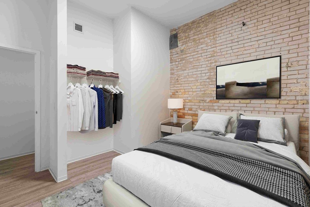 a bedroom with a bed and a brick wall