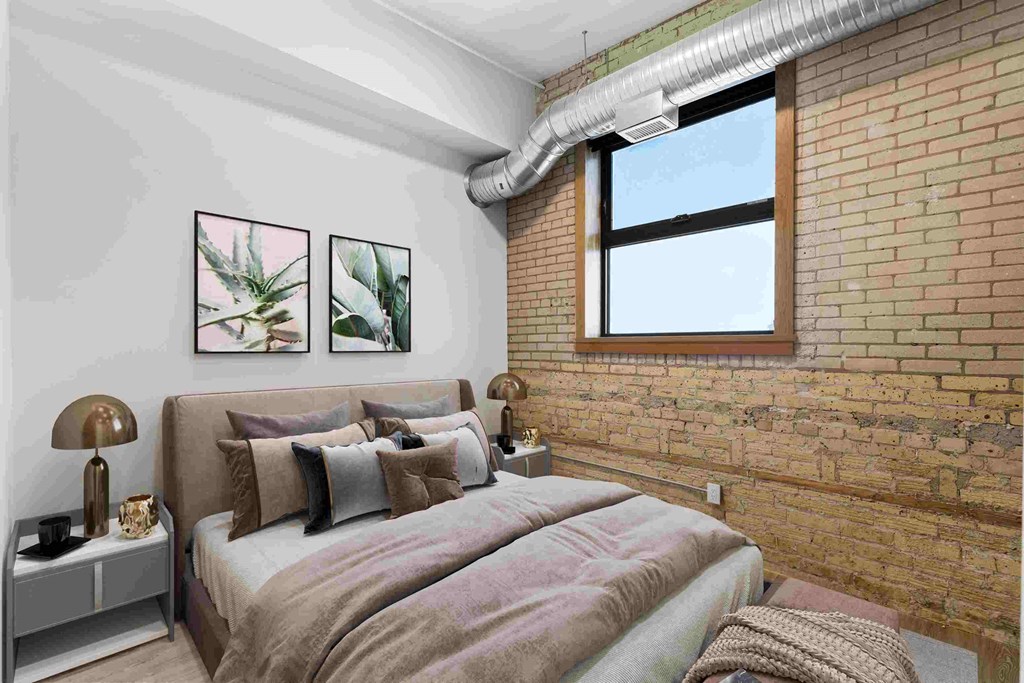 a bedroom with a bed and a exposed brick wall