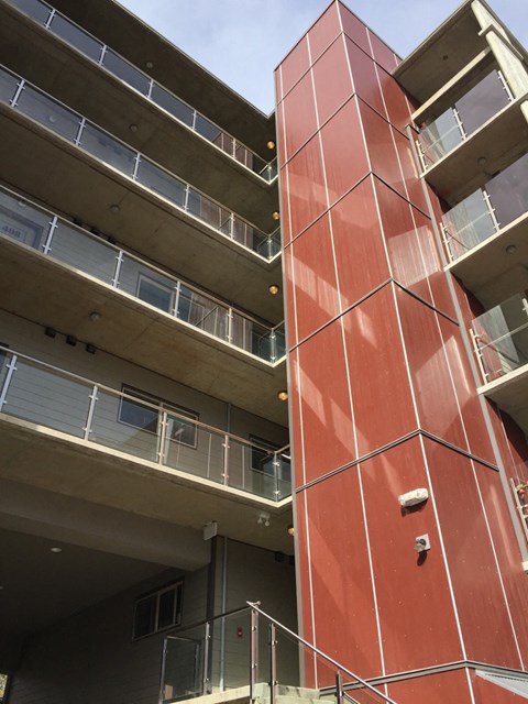 A tall red building with balconies on the second floor.
