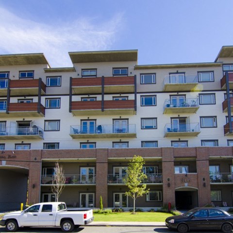 A white pickup truck is parked in front of a two-story apartment building.