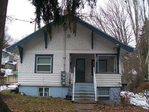 the front of a white house with a blue door