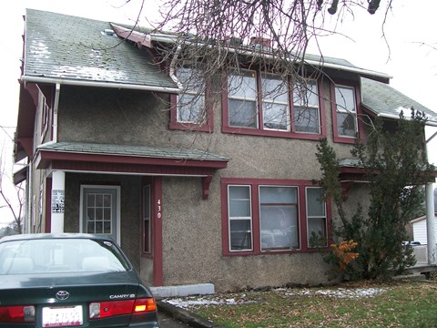 A green car is parked in front of a house.