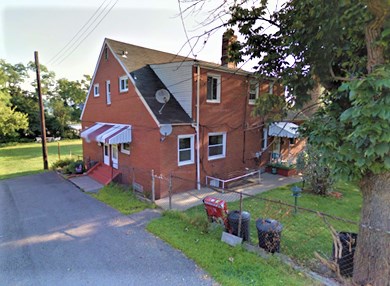 A red brick house with a white awning and a driveway.
