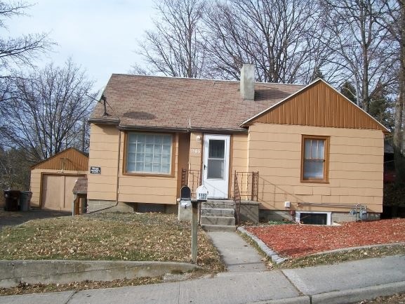 a yellow house with a porch and a sidewalk