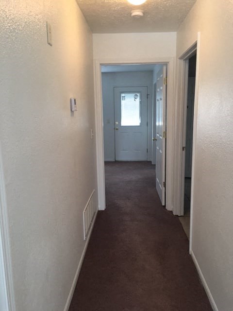 a hallway with a door to a room and a carpeted floor