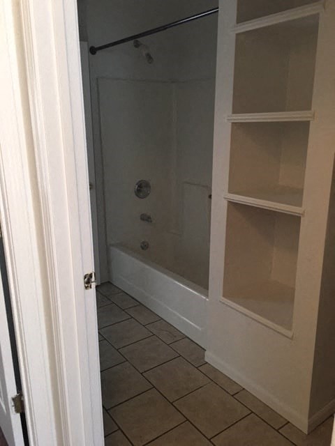 a bathroom with a shower and some white shelves