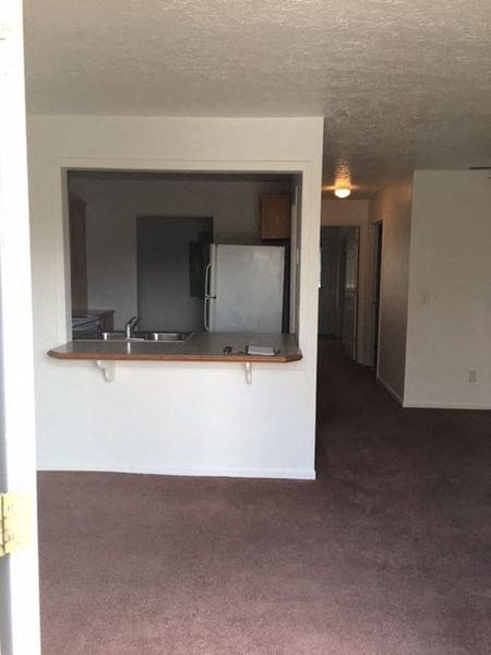 an empty living room with a sink and a refrigerator