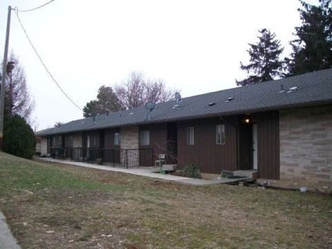 A brown house with a grey roof and a small front yard.