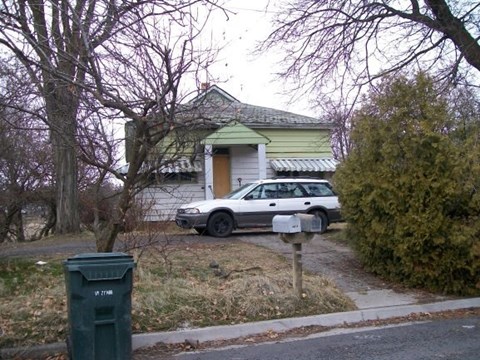 A white car is parked in front of a house.