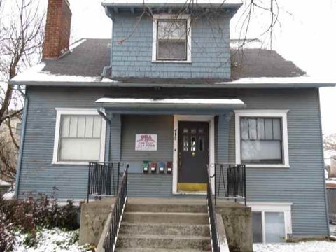 A blue house with a sign that says "For Sale".