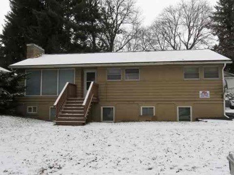 A house with a snow-covered roof and a sign on the front door.