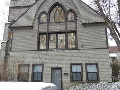 A grey house with a large arched window and a door.