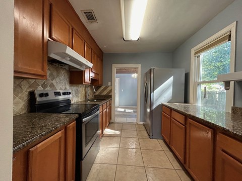 A kitchen with brown cabinets and a black stove top oven.
