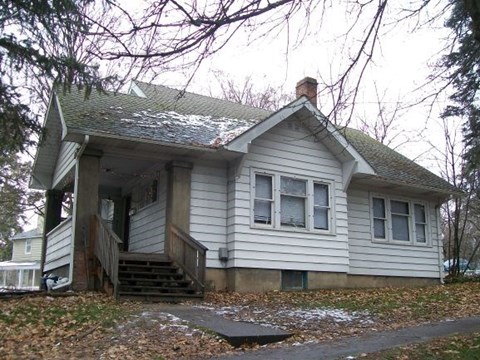 A small house with a grey roof and white siding.